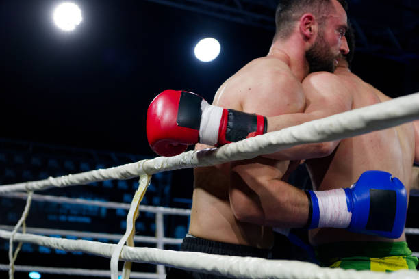 Two young professional boxer having a competition tournament on stage. Attractive male athlete fighters muscular shirtless punches and hitting competitor enjoy boxing exercise in the ring at stadium.