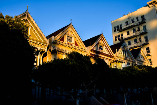 Dolores street in the Mission district of San Francisco, lined by pastel colored victorian houses.
