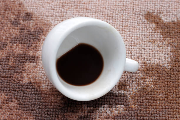 Coffee spilled from white cup on the carpet