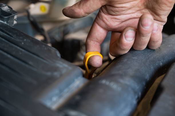 istock An auto mechanic pulls out a dipstick to check the oil level in a car engine. 2160633988