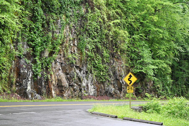 Wet rock wall by highway through the mountains.