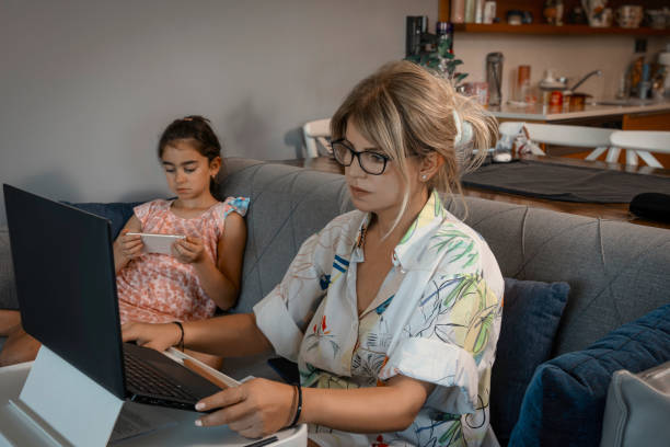 istock Girl playing games on the phone while her mother is working. 2160640101