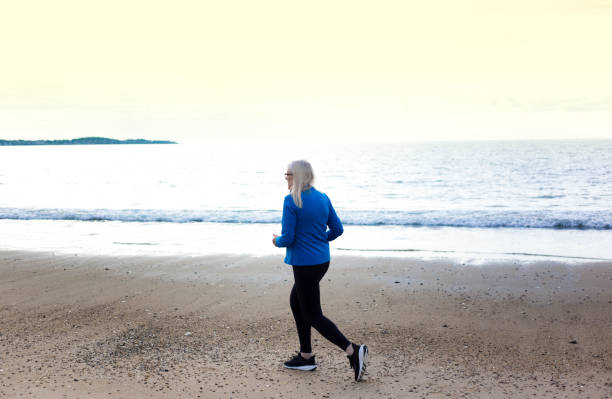istock Active Senior Woman Jogging on Beach 2160641402