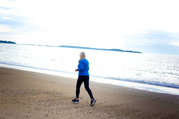 istock Active Senior Woman Jogging on Beach 2160641406