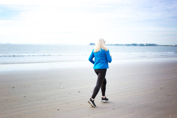 istock Active Senior Woman Jogging on Beach 2160641423