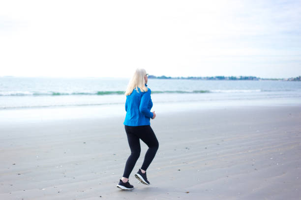 istock Active Senior Woman Jogging on Beach 2160641430