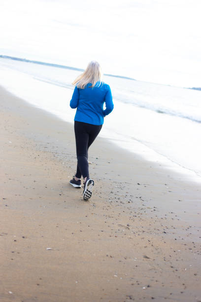 istock Active Senior Woman Jogging on Beach 2160641436