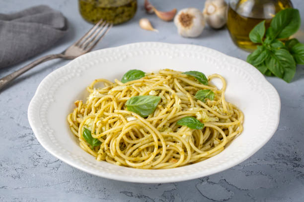 istock Delicious pasta with pesto sauce, basil and cutlery on white background 2160644399