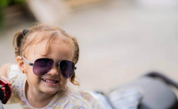 little hispanic latina girl playing outdoors and wearing a pair of sunglasses while smiling happily