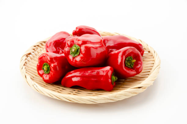 fresh red bell pepper on bamboo strainer on white background