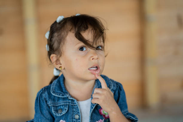 little latina girl playing outdoors with one hand next to her happy face