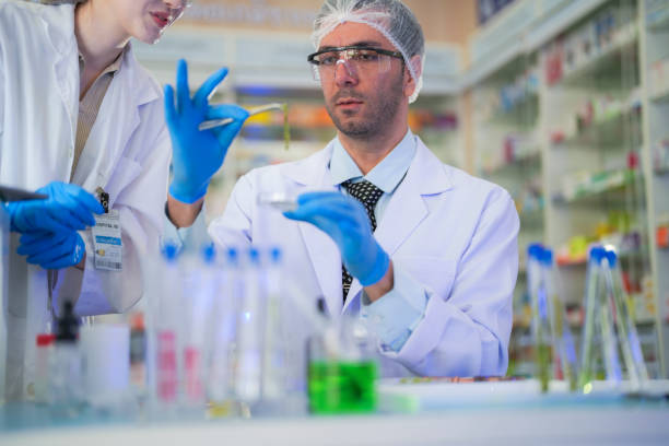istock scientists perform experiments and record data. people arranges equipment with test tubes and chemicals for producing medicine and biochemistry. man hold tubes of chemical liquids and plant samples. 2160656369