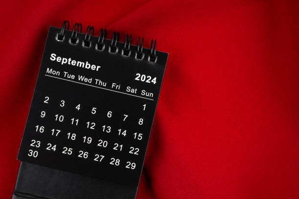 istock September 2024 Black spiral desktop calendar on red textile. 2160658394