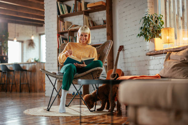 istock Woman reading book and looking at camera at home. 2160661011