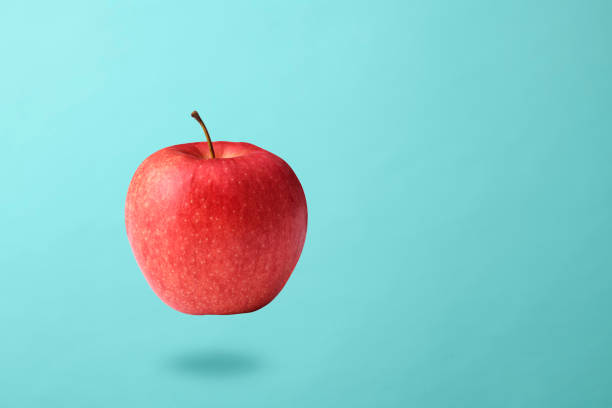 istock Red apple in mid-air against light blue background 2160675677