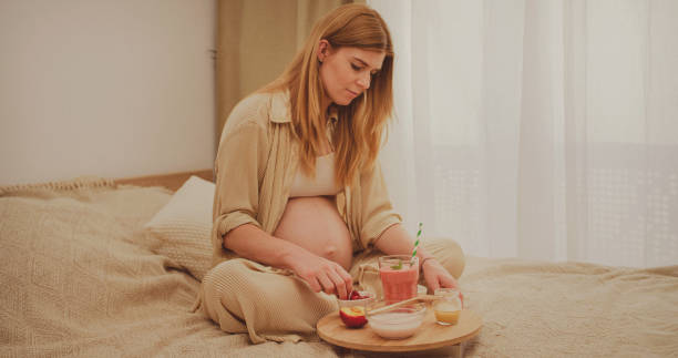 istock A pregnant woman sits on the bed and eats breakfast. 2160677226
