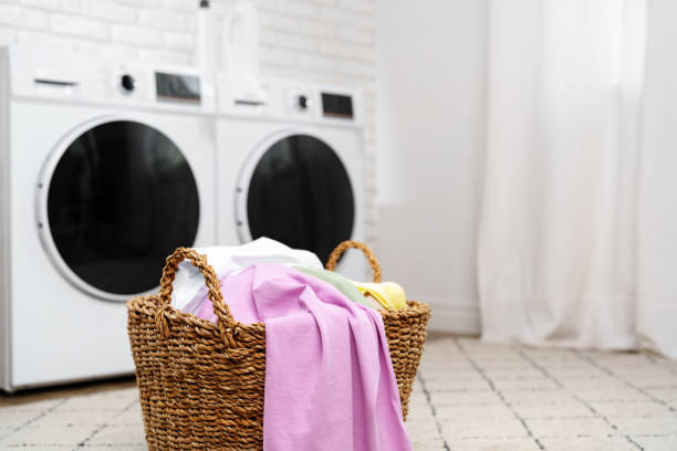 istock Laundry Basket With Clean Clothes in Front of Modern Washing Machines 2160677442