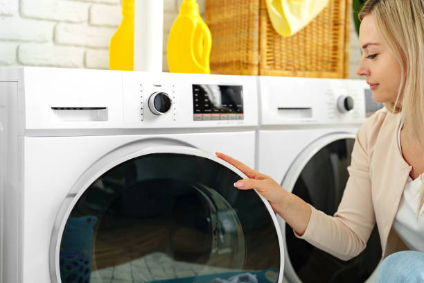 istock Woman Setting Washing Machine Cycle in Laundry Room 2160678915