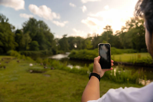 Close up, phone mockup. Young man is taking nature photos with his smartphone.