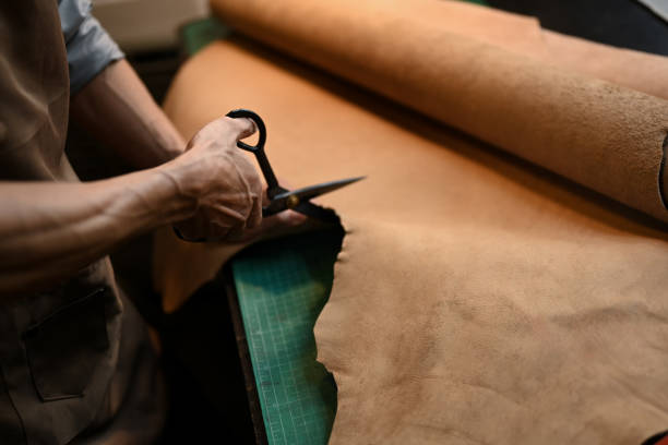 istock Close up an unrecognizable craftsman cutting leather with scissors at table 2160688872