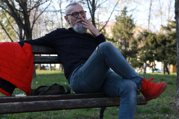istock Modern senior smoking in public park 2160697086