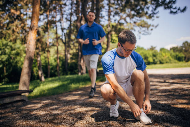 istock Man in blue shirt jogging toward another man kneeling. 2160698621