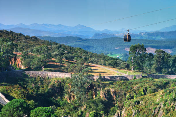 A cable car is flying over a mountain. The sky is clear and blue. Cabarceno Nature Park. Cantabria, Spain.