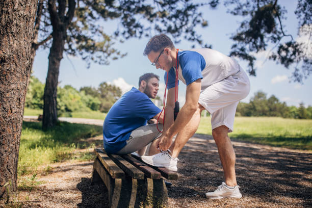 istock Man tying shoelace on bench while friend looks downwards 2160700696