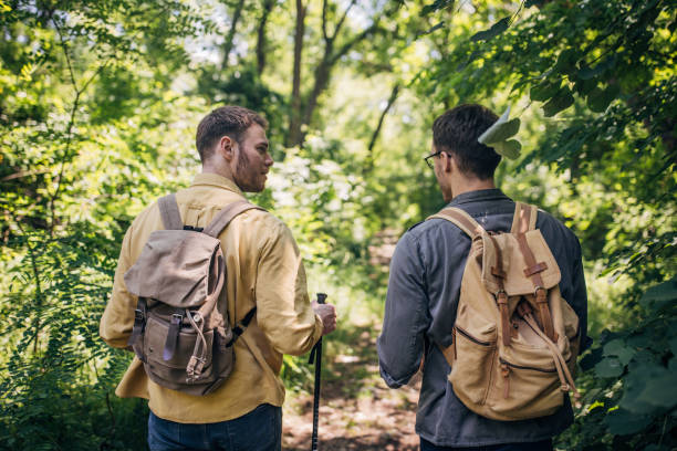 istock Two friends hiking in a green forest with backpacks 2160702602