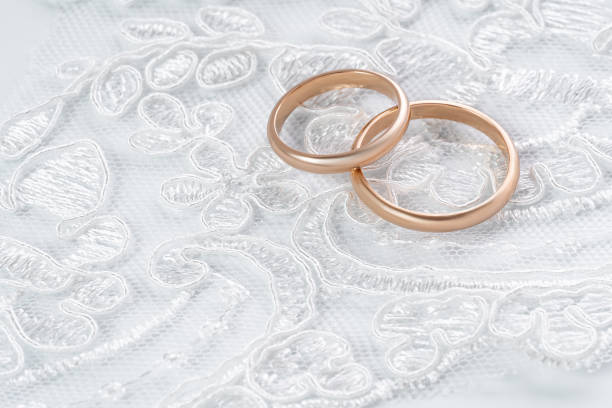 istock Wedding rings lying on a white intricate fabric 2160702804