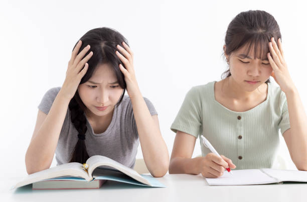istock tired upset student girls grabbing head  in classroom 2160704072
