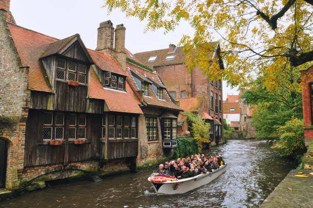 30-10-2014 Brussels, Belgium - Tourists enjoy a boat ride along Bruges canals, admiring historic wooden facades
