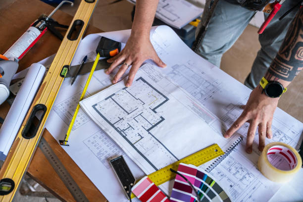 istock Unrecognisable handyman reviewing architectural blueprints at the table with construction work tools at site 2160707997