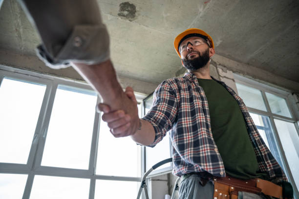 Handshake at construction site. Construction worker handshakes hands with a home owner