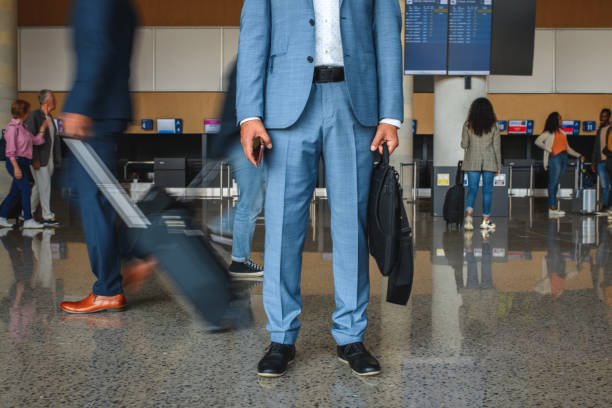 Side view of caucasian male business person walking in front of white background wearing businesswear who is smiling and holding briefcase