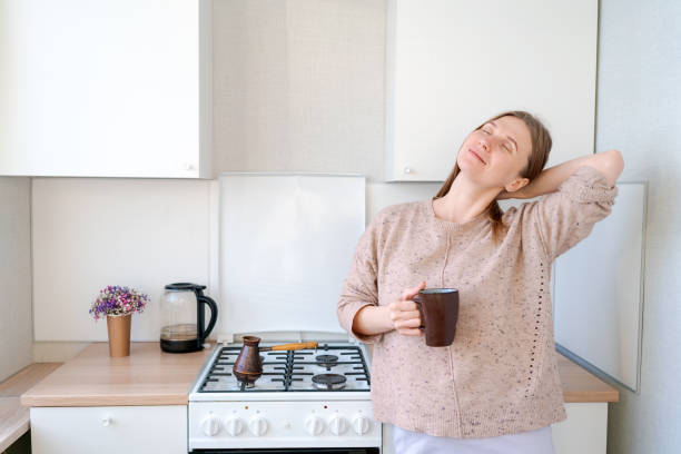 istock A woman is sitting in a kitchen with a mug in her hand 2160713843
