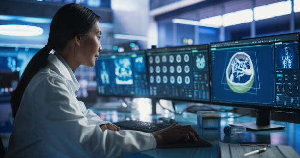 istock Female Asian Neurologist Using Desktop Computer With Human Brain MRI Scans In Modern Medical Research Center Laboratory. Professional Doctor Looking At Patient's Brain In 3D Software, Finding Tumors. 2160715434