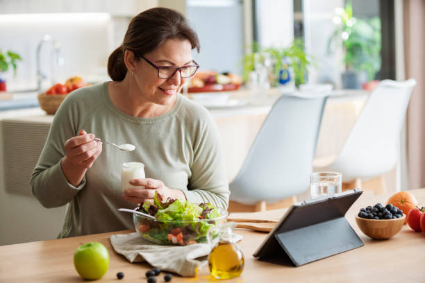istock Woman is eating healthy meal at home while using digital tablet 2160717040