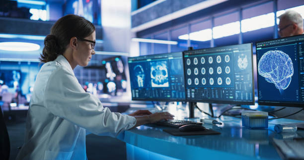 istock Caucasian Female Neuroscientist Using Desktop Computer To Analyze CT Scans Of Human Brain In Busy Research Center Laboratory. Proffesional Doctor Finding Solutions for Brain Damage, Cancer Treatment. 2160717320