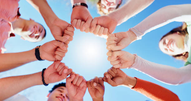 istock Friends, people and group with fist bump or below for teamwork, unity and support in circle outdoor. Hands, team building and solidarity for collaboration, partnership and motivation with diversity 2160723971
