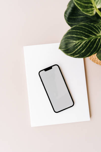 istock Blank path screen mobile phone with mockup on various notepads on beige background. 2160725836
