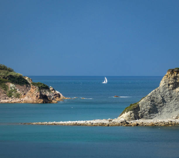 Beautiful morning seascape, a white sailboat sailing in the distance against the backdrop of majestic mountains. Beauty of Turkish nature