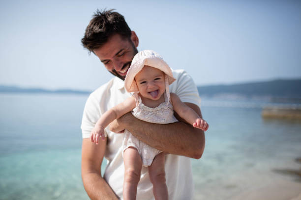 Little baby having fun with dad on the beach