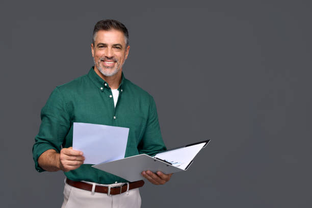 istock Smiling middle aged business man adviser holding documents isolated on gray. 2160740650