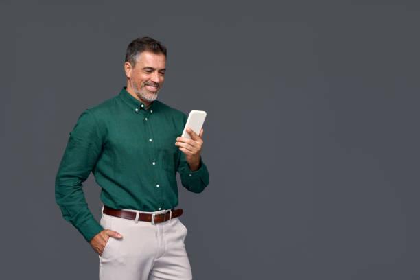 istock Smiling middle aged business man using mobile phone isolated on gray background. 2160741860