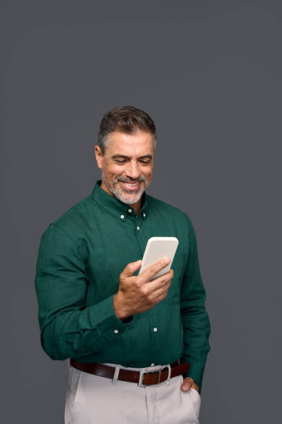 istock Happy older business man using mobile phone isolated on gray background. 2160741874
