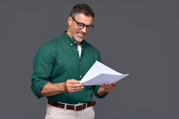Smiling middle aged business man adviser holding documents isolated on gray.