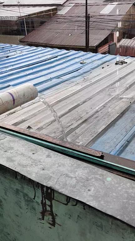 Closeup of roof tiles during heavy rain. A closeup of a roof with galvanised and gutter with water pouring out and rain drops falling down on the roof