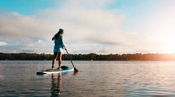 istock Standing woman, back and paddle board in river for calm exercise with summer vacation, training and sports in water. Girl, balance and floating in lake for wellness, holiday sunset and cardio workout 2160748040