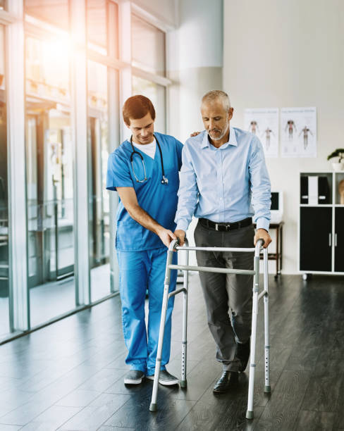 istock Physiotherapist, senior man and walking frame with help, balance and guide for steps in hospital. Doctor, elderly person and mobility aid for recovery, rehabilitation and support with care at clinic 2160748437